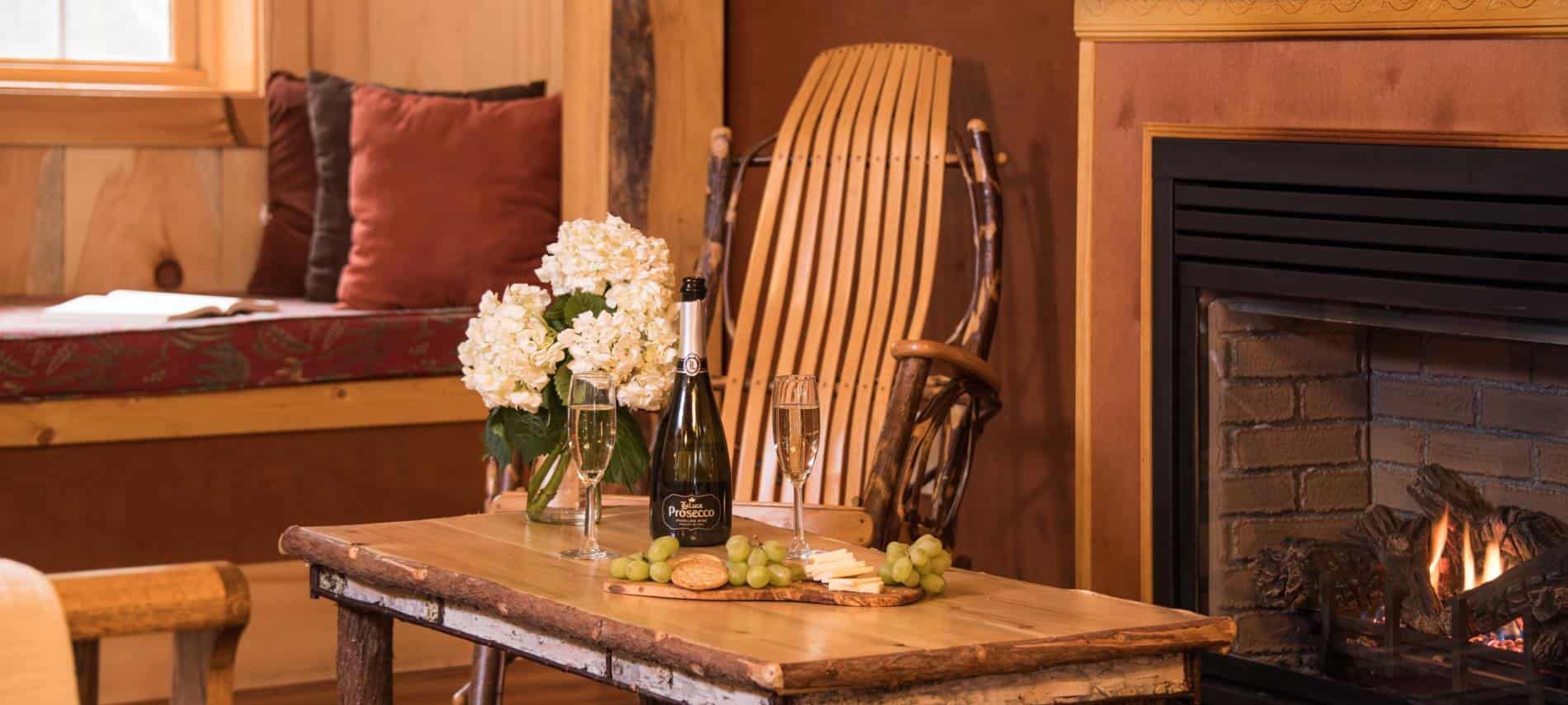 Rustic coffee table topped with Champagne bottle, two flutes, green grapes, crackers and cheese