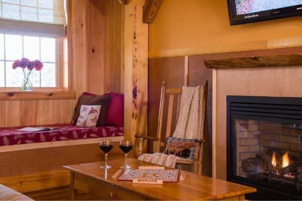 Blackberry Bend living area, fireplace with fire, coffee table topped with wine and Scrabble board and built-in window seat