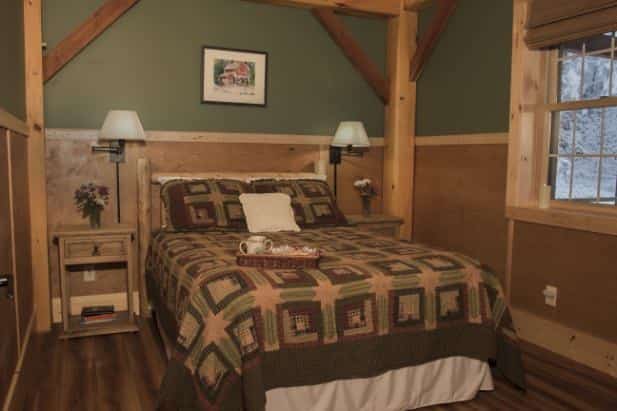 Evening Star guest room with wood floor, window, bed with rustic bedding and two nightstands with lamps