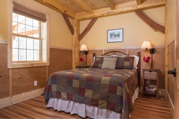 Hemlock Hideaway guest room with wood floor, beds with quilted bedding, nightstands with lamps and large window