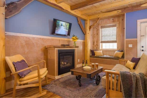 Hemlock Hideaway cabin's living area with fireplace, window and window seat, and coffee table topped with popcorn and beer