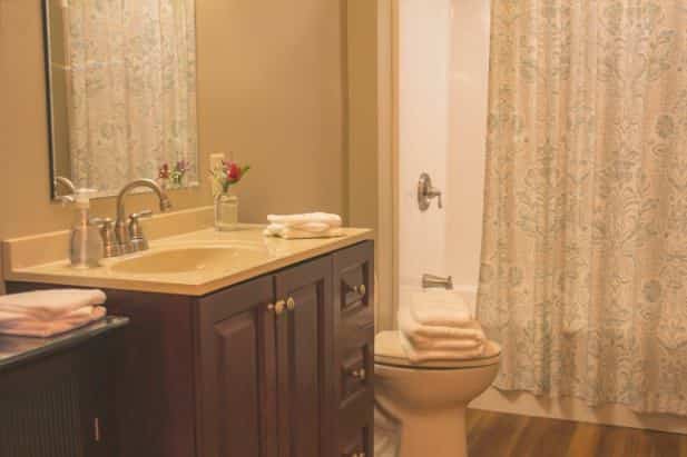 Peak Perspective bath with tub/shower, vanity with sink and mirror, wood floor, and white towels