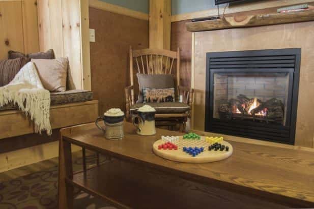 Peak Perspective living area, fireplace, rocking chair, built-in window seat, coffee table with hot cocoa and Chinese checkers