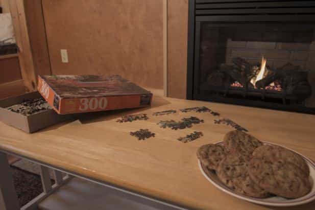 Serene Outlook cabin coffee table topped with fresh baked cookies and a puzzle in front of a warm fire