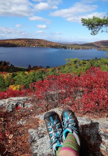 Stunning view of the area from a rocky hilltop in the fall, colorful leaves all around, and distant hills surrounding a large lake