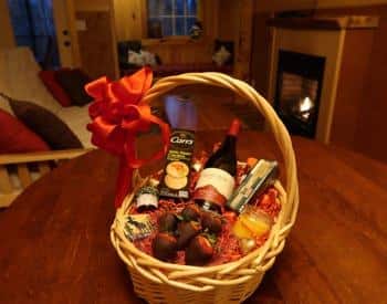 Oval basket with handle filled with wine, crackers, cheese and chocolate covered strawberries